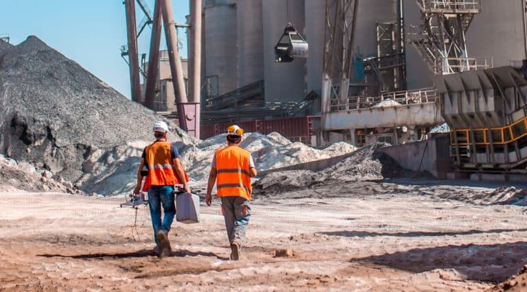 People are working in the industry. Modern technologies work at a cement plant. Technological work on the production of cement. Working atmosphere with copy space. Heaps of sand and soil raw materials