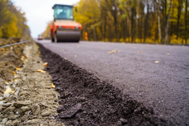 Road repair, compactor lays asphalt. Heavy special machines. Asphalt paver in operation. Side view. Closeup.